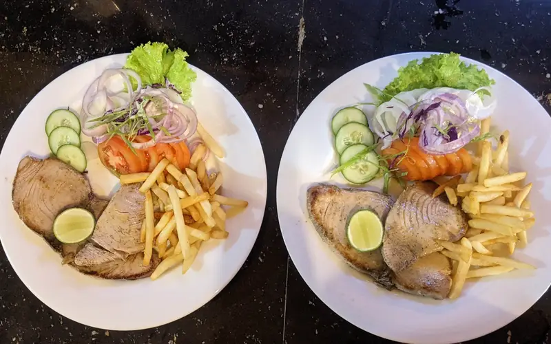 Two plates of grilled tuna steak with salad and fries at the Surfing Life restaurant
