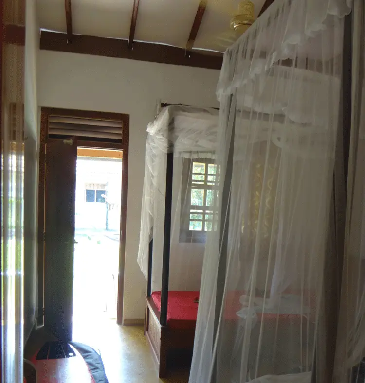 Twin room at Surfing Life with mosquito nets over the beds and a surfboard by the door