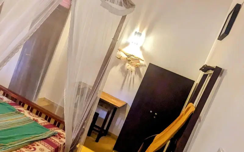 A deluxe room at Surfing Life with a four-poster bed, mosquito net and ceiling fan