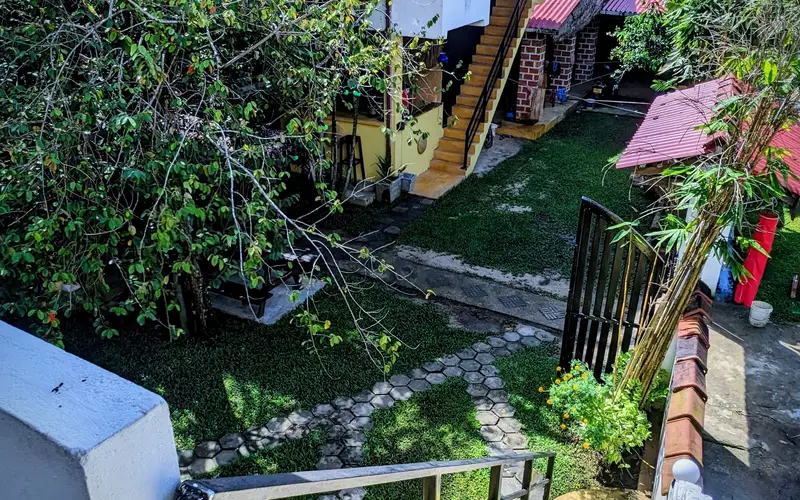 Sunny view over the tropical garden and buildings at Surfing Life Guest House, Weligama
