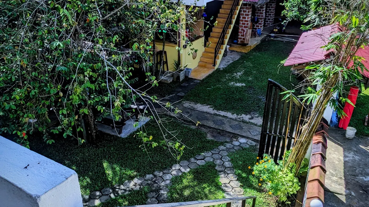 Sunny view over the tropical garden and buildings at Surfing Life Guest House, Weligama